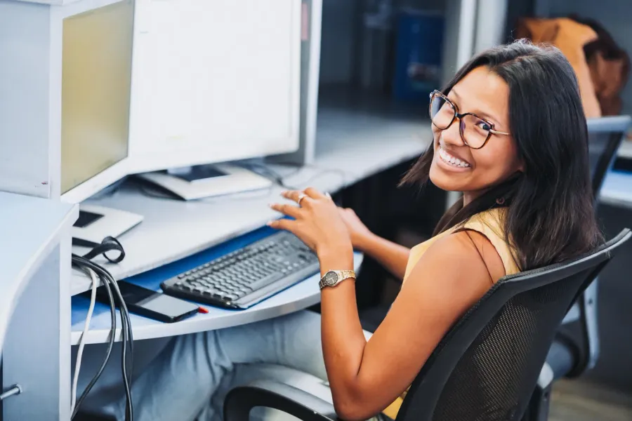 Conseillère souriante à son poste de travail, équipée de deux écrans