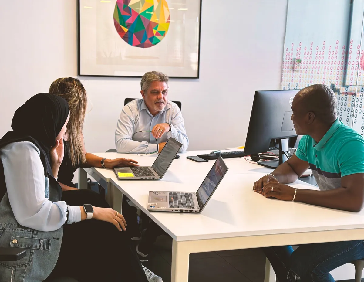 Un responsable échange avec trois collaborateurs autour d’une table de réunion